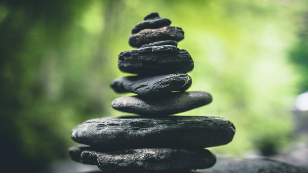 A stack of seven flat stones balanced on top of each other, resembling a serene content hub, set against a blurred green natural background.