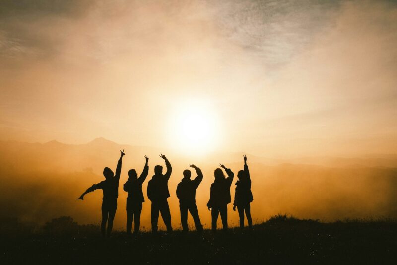 silhouette photo of six persons on top of mountain working together for success