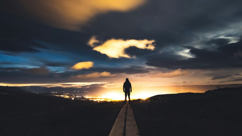 a person standing on a road at sunset representing a journey with challenges,