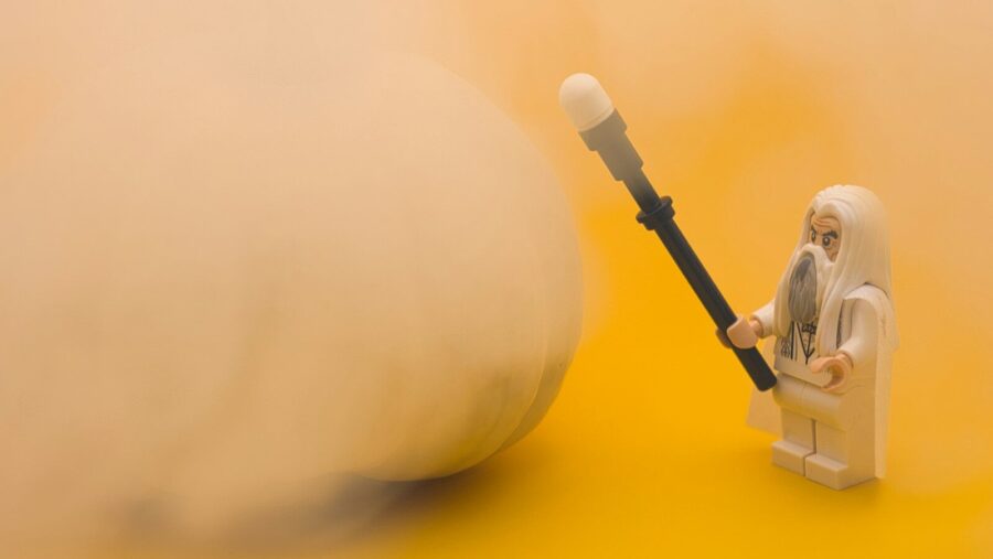 a lego figurine holding a large object on a yellow background, brainwashing