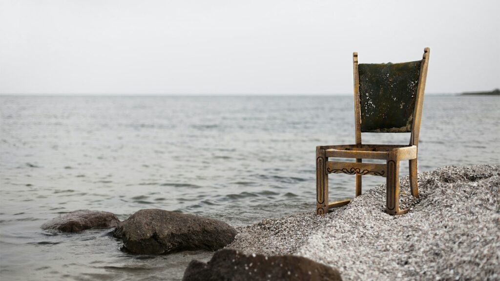 brown wooden parsons chair on gray beach sand: back pain support