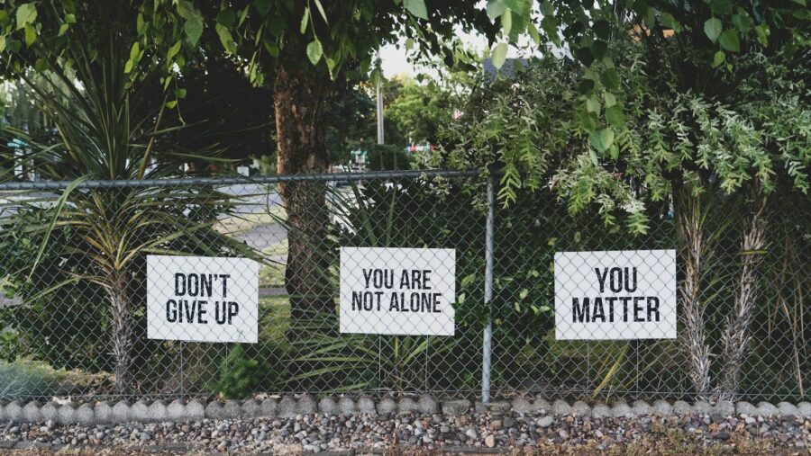 don't give up. You are not alone, you matter signs on metal fence: suicide prevention narrative