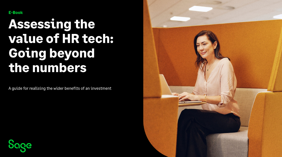 A woman sitting in an office booth working on a laptop. Text reads: "E-Book: Assessing the value of HR tech: Going beyond the numbers.