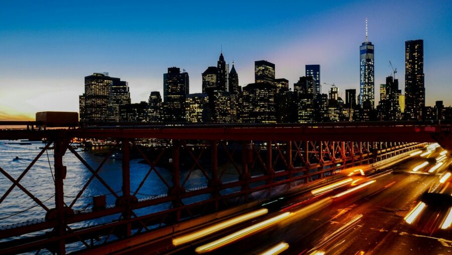 A long-exposure shot of light trails on the freeway with the New York city skyline at the back: mobilities