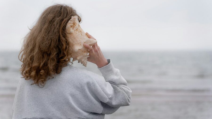 a woman holding a seashell up to her face, social model of disability.