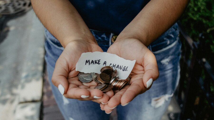 person showing both hands with make a change note and coins