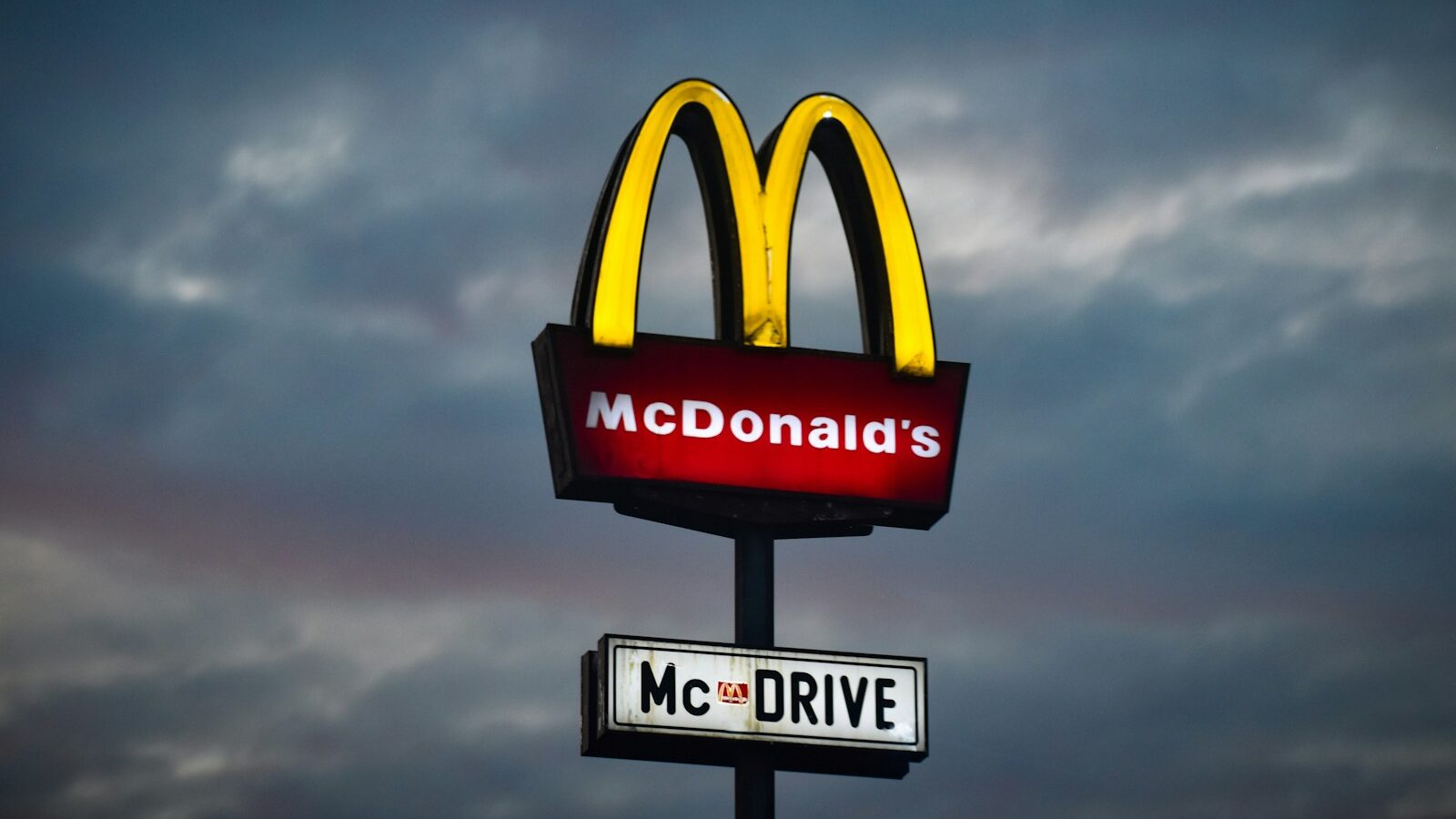 a mcdonald's sign with a cloudy sky in the background, McDonald’s faces new harassment claims