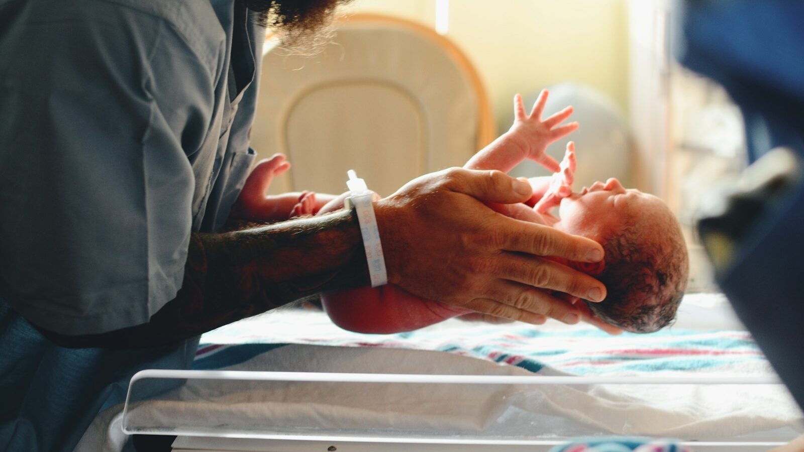 Neonatal care leave, person wearing gray shirt putting baby on scale