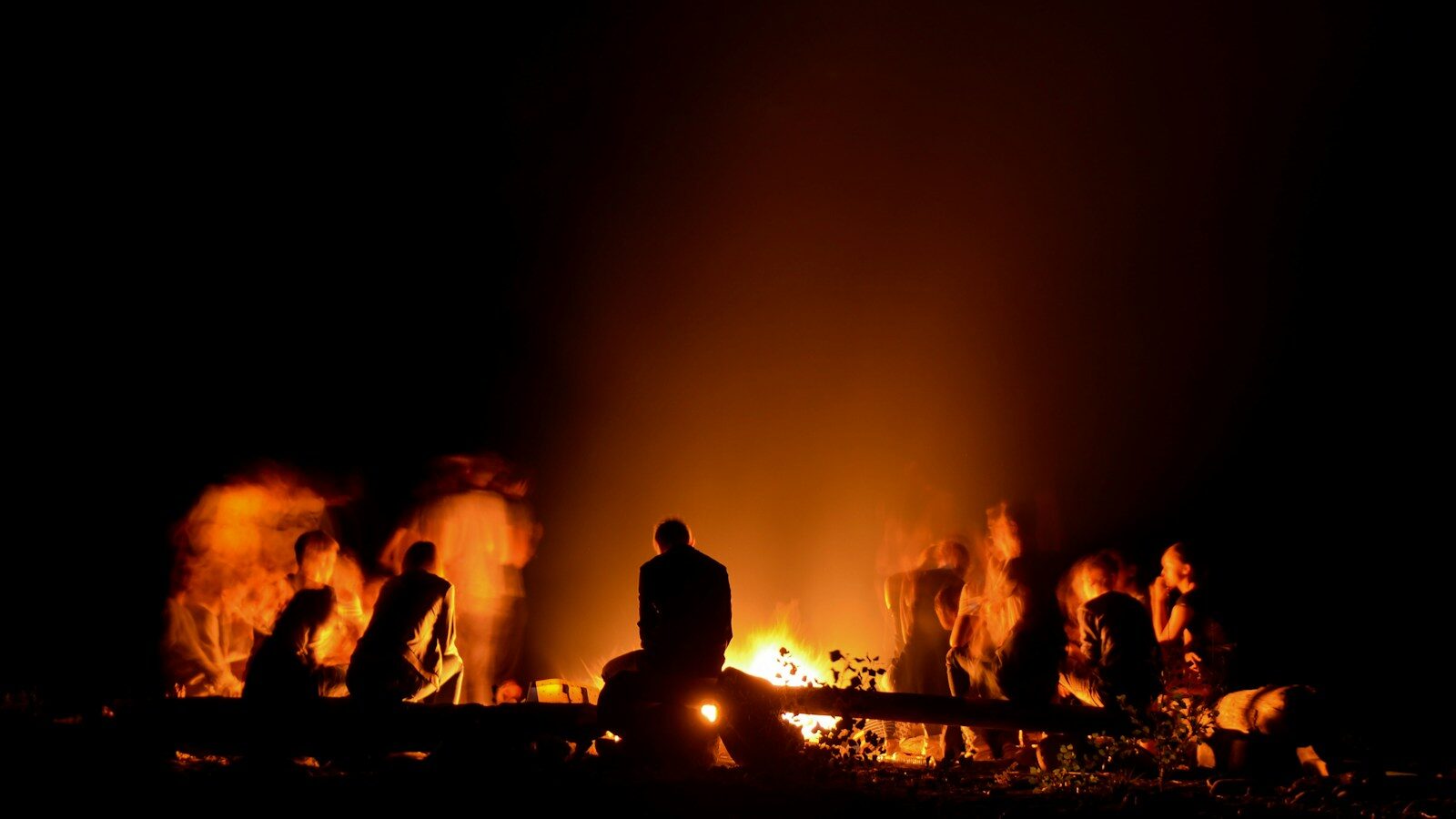 people gathered around camp fire at nighttime - intergenerational inclusion