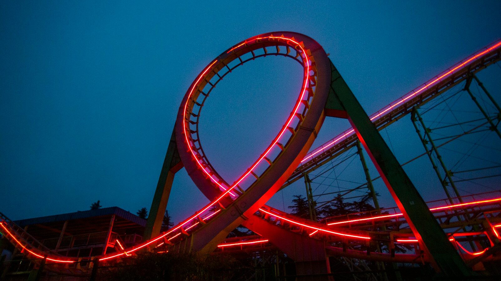 a roller coaster lit up at night with red lights, depicting the loneliness-conflict loop