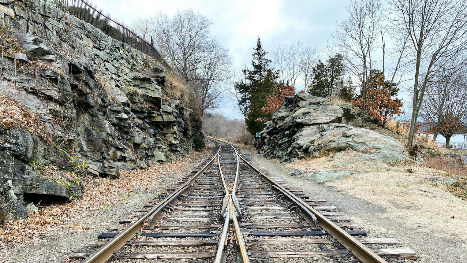 brown metal train rail near rocky mountain during daytime, depicting the concept of mergers and acquisitions (M&As)