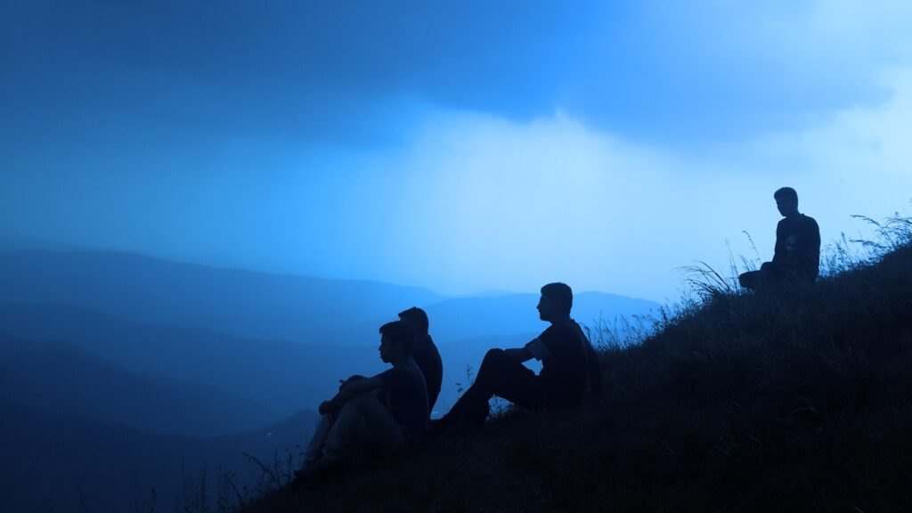 silhouette of men sitting on mountain, depicting men's mental health concept