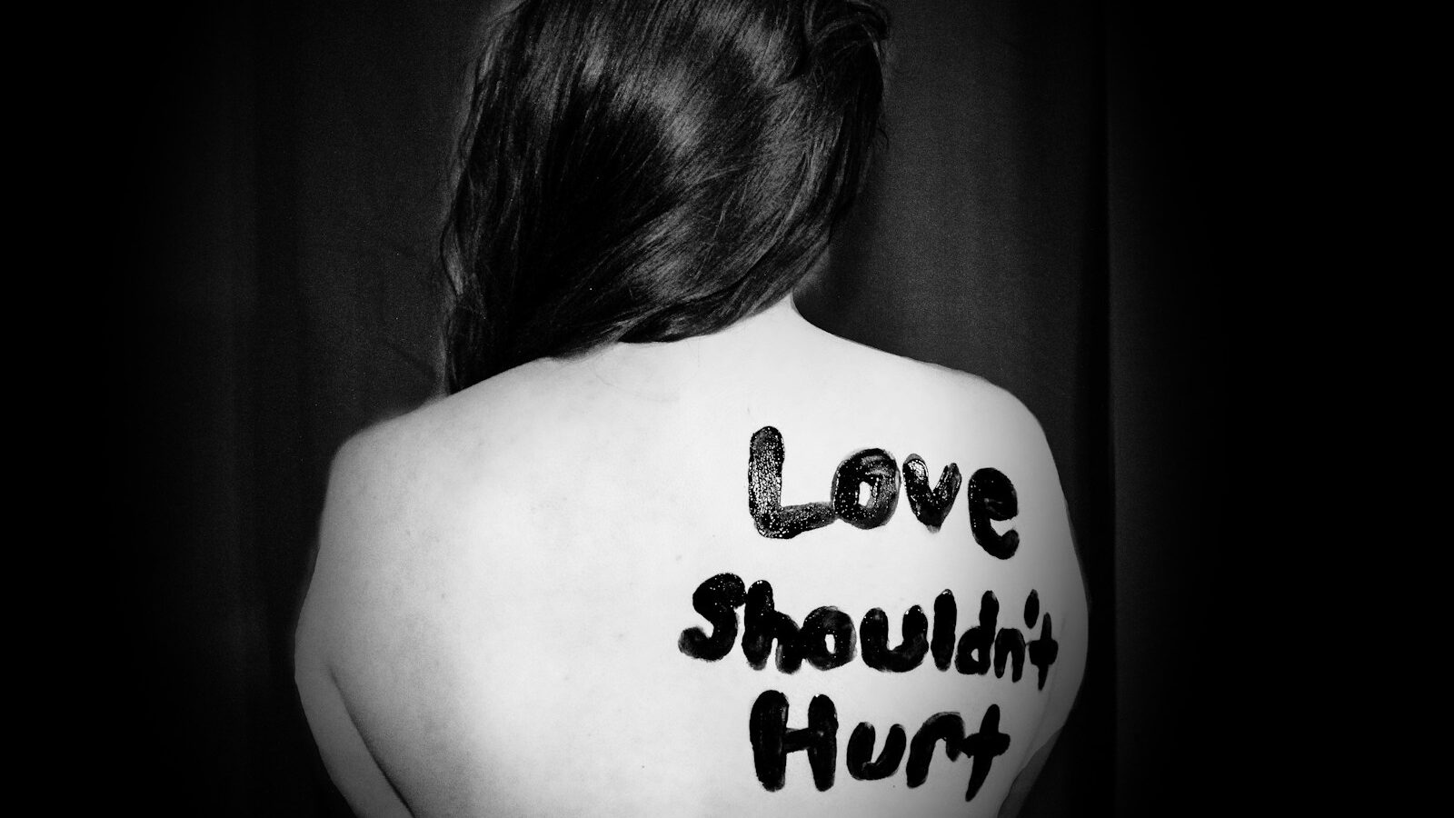 love shouldn't hurt-printed on back of woman, disclosing domestic abuse
