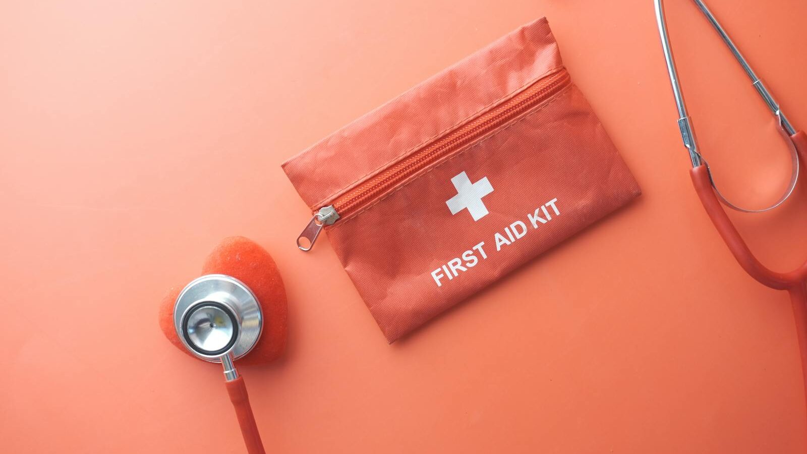 Medical tools including a stethoscope and first aid kit on a pink surface, perfect for healthcare themes. Depicting AI mental health tools as a band-aid.