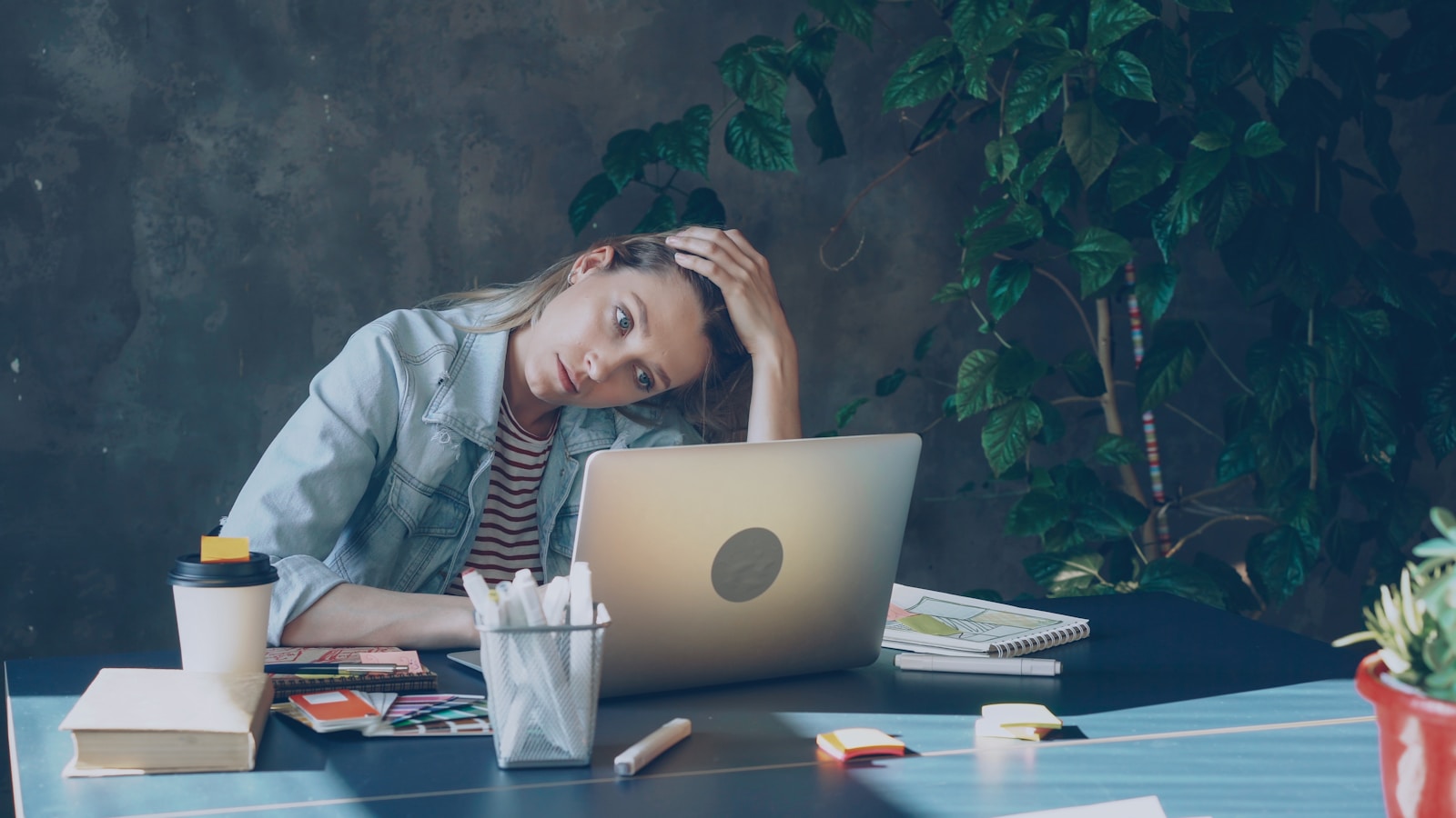 A woman appears stressed while working on laptop. Return to office.