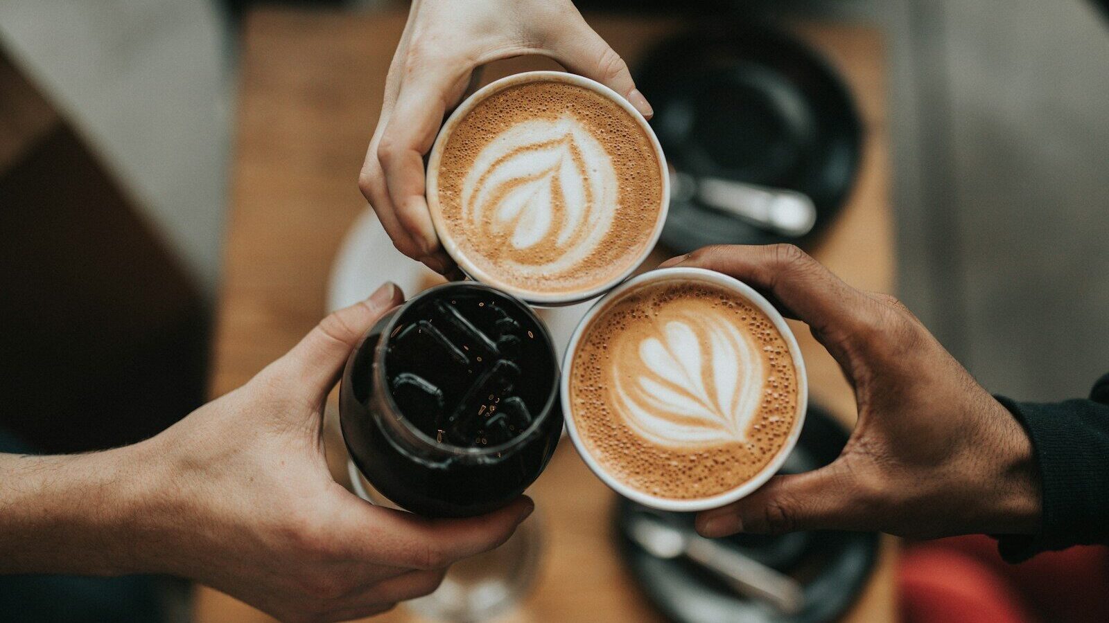 person holding cappuccino in black ceramic mug
