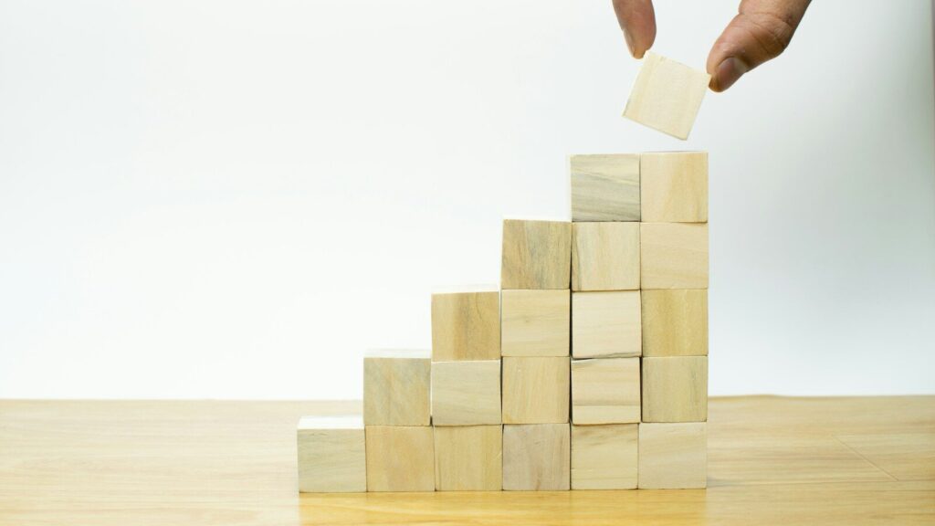 A person placing a piece of wood into a pyramid